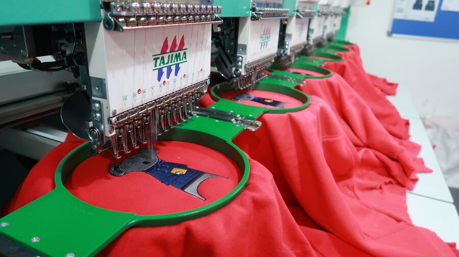 Máquina bordando logo sobre prenda roja